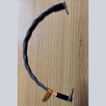 Černý audio kabel s pleteným obalem a konektory typu jack. Na spodním konektoru je hnědý kožený pásek s vyraženým nápisem sonorus a menším textem pod…