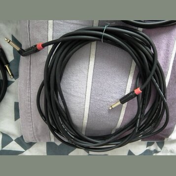 Černý instrumentální kabel s pravoúhlým a rovným konektorem typu jack. Oba konektory mají červené označení u základny. Na povrchu kabelu je viditelný…