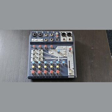 Mixážní pult Soundcraft NOTEPAD-BFX v tmavě šedé barvě s kovovými prvky. Na předním panelu jsou vidět různé vstupy, potenciometry a červené tlačítka.…