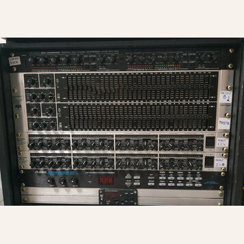 Sestava rackového vybavení v kovovém case. Obsahuje zařízení s nápisy „ALESIS 3630 COMPRESSOR RMS/PEAK DUAL CHANNEL COMPRESSOR LIMITER WITH GATE“, dv…