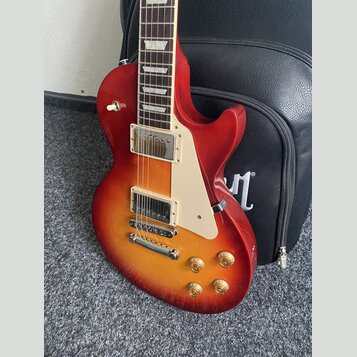 Elektrická kytara s tmelem v červeno-žlutém sunburst provedení a bílým pickguardem. Nástroj má dva humbuckery s krémovými rámečky, čtyři zlaté ovláda…