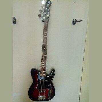 Čtyřstrunná basová kytara s černým korpusem v červeném sunburst provedení a bílým pickguardem. Na hlavě je svisle napsaný nápis RIS BASS. Nástroj má…