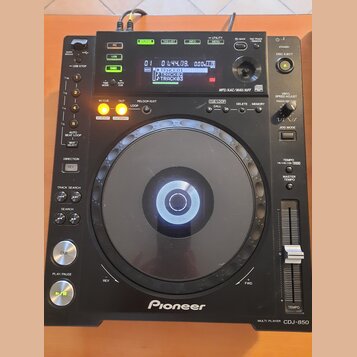 Černý digitální DJ player značky Pioneer, model CDJ-850 MULTI PLAYER. Zařízení má velký kruhový jog wheel, fader tempo a řadu ovládacích tlačítek s n…