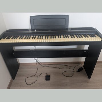 Černý digitální piano s klaviaturou a integrovaným stojanem. Na horní části je nápis KORG a nad klávesami je umístěna černá hudební stránkovka. Nástr…