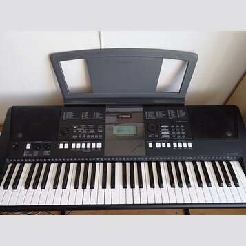 Černý digitální klavír s bílými a černými klávesami. Na horním panelu je v centru logo YAMAHA a v pravé části nápis PSR-E423. Nástroj obsahuje řadu t…