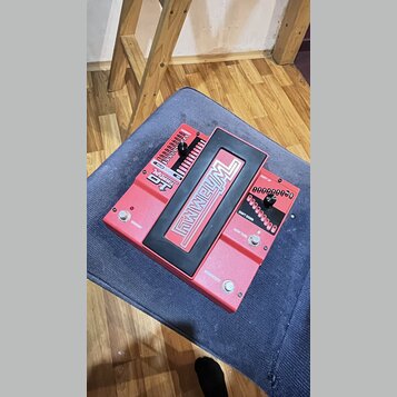 Červený kytarový pedál s černým rámečkem a ovládacími prvky. Na horní části je velký bílý nápis FWELM a menší nápisy DT, WHAMMY, SHIFT UP, SHIFT DOWN…