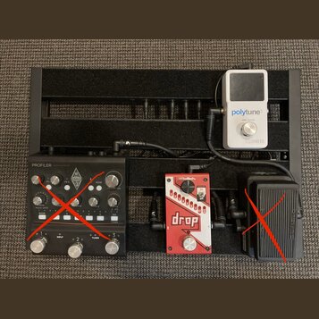 Černý kovový pedalboard s třemi efekty. Vlevo je černý přístroj s nápisy PROFILER a KEMPER, vpravo nahoře bílý pedál s nápisy polytune 3 TRUE BYPASS…