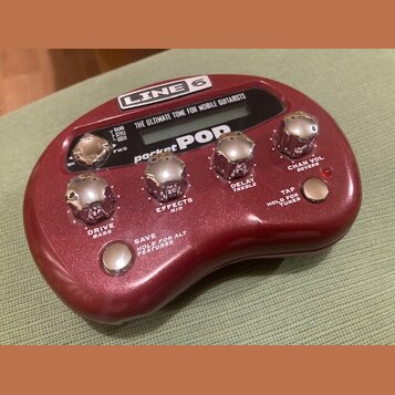 Vínový efektový procesor s nápisy LINE 6 a pocket POP. Zařízení má pět chromovaných otočných ovladačů s popisky DRIVE BASS, EFFECTS MID, DELAY TREBLE…