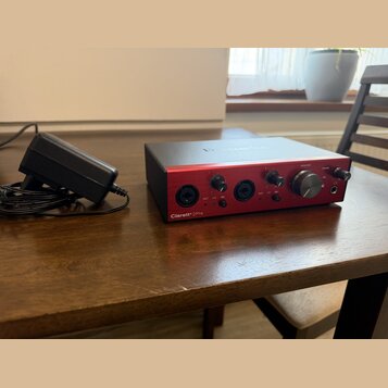 Černý audio rozhraní s červeným předním panelem a nápisem Clarett+ 2Pre. Na horní straně je bílý nápis Focusrite. Zařízení má několik ovládacích knof…