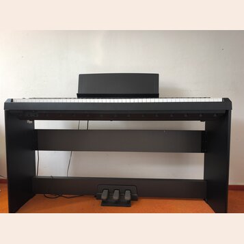 Černý digitální piano v černém stojanu s třemi pedály. Nástroj má bílé a černé klávesy a nad nimi je umístěna černá překrytka. Na povrchu nejsou vidě…