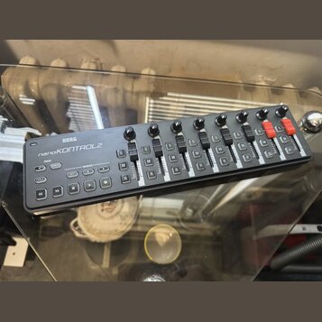 Černý MIDI kontrolér s nápisem KORG a nanoKONTROL2. Zařízení obsahuje osm posuvníků, osm otočných knoflíků a několik malých tlačítek s označením TRAC…
