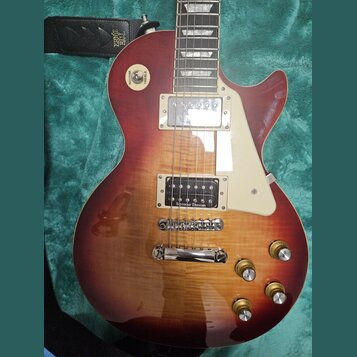 Elektrická kytara typu Les Paul s červeně-žlutým sunburst lakem a viditnou strukturou dřeva. Na hmatníku jsou vidět vložky ve tvaru trapézů a na těle…