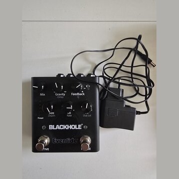 Černý kytarový efekt s nápisy BLACKHOLE a Eventide. Zařízení má šest ovládacích knoflíků s popisky Mix, Gravity Delay, Feedback Q, Size Depth, L.O Ra…