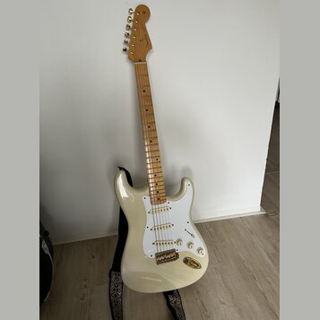 Elektrická kytara s bílým trupem, bílým pickguardem a světle hnědým hnedobělým hmatníkem. Na hlavě je nápis "Fender" a v dolní části hmatníku u 12. p…