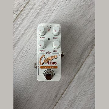Bílý efekt pedál s nápisy ehx, Canyon ECHO a NYC DSP. Pedál má čtyři bílé otočné ovladače s popisky BLEND, DELAY, FILTER a FDBK a jedno tlačítko TAP…