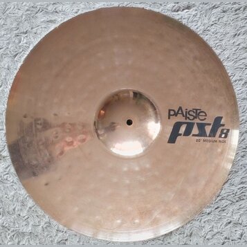 Kruhový činel z bronzu s viditelným kovánívým vzorem v podobě drobných jamů. Na povrchu je černý nápis pAiste pst8 a pod ním text 20" MEDIUM RIDE. Po…