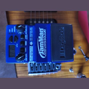 Modrý loop pedál značky DigiTech s nápisem JamMan STEREO LOOPER/ PHRASE SAMPLER/SOLOXT. Zařízení má černý stoupací spínač s vyraženým logem DigiTech,…