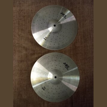 Dva kovové činely v barvě stříbra s koncentrickými drážkami na povrchu. Oba mají v horní části nápis ABX Cymbals a v dolní části označení 14" HIHAT.…