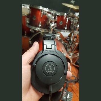 Černé uzavřené sluchátka s nápisem ATH-M30x a logem značky Audio-Technica v kruhu. Povrch plastu vykazuje drobné známky používání a lehké znečištění.…
