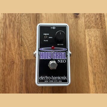 Kytarový efekt pedál v bílém rámu s černým předním panelem. Na panelu je nápis HOLY GRAIL NEO, značka electro-harmonix a text NEW YORK CITY, USA. Obs…