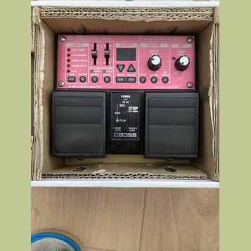 Černý efekt pedál Boss RC-30 Loop Station s červeným předním panelem a dvěma velkými stoupacími spínači. Na panelu jsou nápisy RC-30 DUAL TRACK LOOPE…