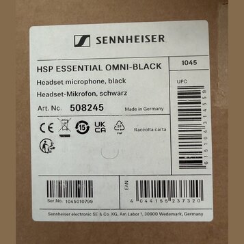 Fotografie etikety na krabici od produktu s nápisy SENNHEISER a HSP ESSENTIAL OMNI-BLACK. Je zde uveden popis Headset microphone, black / Headset-Mik…
