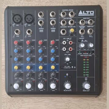 Šedý mixážní pult značky ALTO PROFESSIONAL. Na panelu jsou čtyři vstupní kanály označené CH1 až CH4, sekce BLUETOOTH a MAIN OUT. Jsou zde viditelné n…
