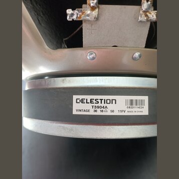 Detail zadní části reproduktoru s kovovým rámem a magnetem. Na magnetu je bílá nálepka s nápisy CELESTION, T3904A, VINTAGE 30 16 Ω 50 11FV a MADE IN…