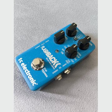 Modrý efekt pedál s nápisy FLASHBACK DELAY AND LOOPER a tc electronic. Na horní straně jsou čtyři černé oválné ovládací knoflíky a přepínače s popisk…