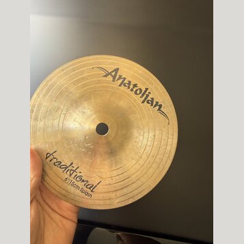 Zlatavý mosazný činel typu splash s viditelným rýhováním. Na povrchu je nápis „Anatolian“ v horní části a v dolní části text „traditional 6"/15cm Spl…