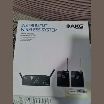 Fotografie znázorňuje krabici s bezdrátovým systémem pro nástroje značky AKG by HARMAN. Na obalu je nápis INSTRUMENT WIRELESS SYSTEM a model WMS40 MI…