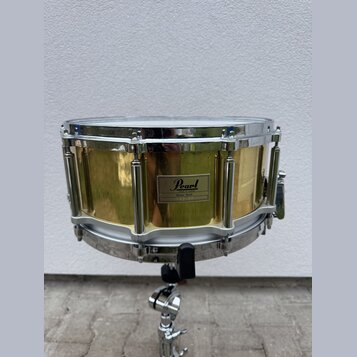Zlatý buben s chromovanými obručemi a mechanismy, umístěný na chromovaném stojanu. Na korpusu je čtvercový štitek s nápisy Pearl, MADE IN TAIWAN a Br…