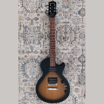 Elektrická kytara s černým korpusem v přechodovém odstínu do hnědého (sunburst) a tmavým hnedým hmatníkem. Na hlavě je bílý nápis Epiphone a vpravo p…
