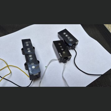 Tři černé elektrické snímače kytary s viditelnými kulatými magnety. Na dvou z nich je bílý nápis MEHTNUI TE. Snímače mají připojené vodiče v barvách…