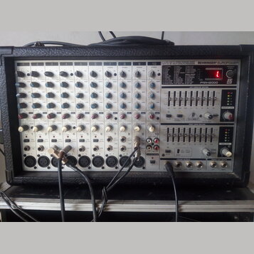 Stříbrošedý napájený mixážní pult v černém kufrovém pouzdře. Na předním panelu jsou nápisy BEHRINGER EUROPOWER, 2 X 250-WATTS STEREO POWERED MIXER WI…