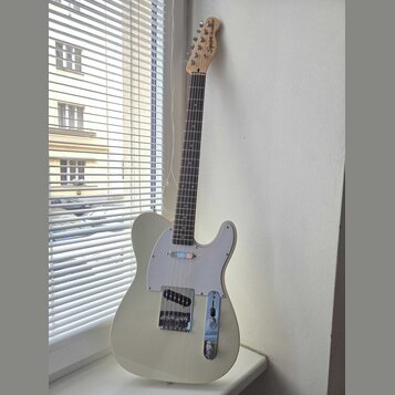 Světle šedá elektrická kytara s bílým pickguardem a hnedým hmatníkem. Na hlavě je nápis Squier by Fender TELECASTER. Nástroj vykazuje známky běžného…