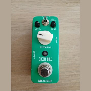 Zelený efekt pedál s bílým ovládacím knoflíkem a dvěma černými menšími knoflíky. Na zařízení jsou nápisy LEVEL, TONE, INPUT, OUTPUT a OVERDRIVE, v ho…