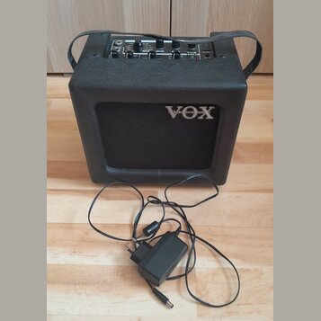 Černý kytarový kombo zesilovač s logem VOX na předním mřížkovém krytu. Horní ovládací panel obsahuje několik potenciometrů a nápisy včetně modelu MIN…