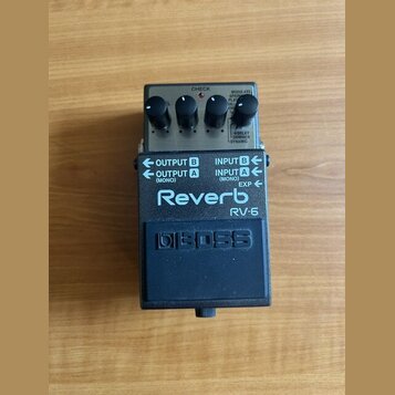 Efektový pedál Reverb značky BOSS, model RV-5. Zařízení je v černém kovovém provedení s šedým horním panelem, na kterém jsou čtyři ovládací knoflíky…
