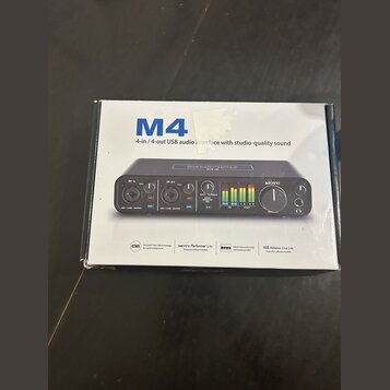 Fotografie znázorňuje krabici od USB audio rozhraní. Na krabici je velký modrý nápis M4 a text 4-in / 4-out USB audio interface with studio-quality s…