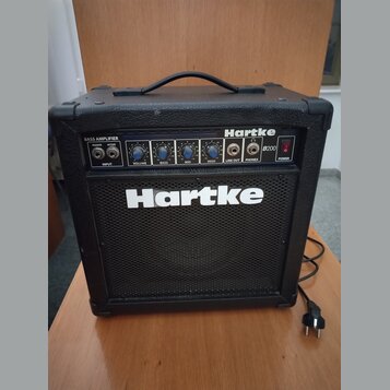 Černý basový kombozesilovač s nápisy Hartke a B200. Horní ovládací panel obsahuje vstup INPUT s přepínačem PASSIVE/ACTIVE, čtyři modré otočné ovladač…