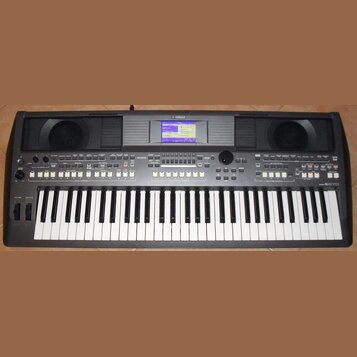 Šedý digitální klavír s nápisem YAMAHA v horní části. V pravém dolním rohu je označení modelu PSR-S570. Nástroj má vestavěný displej, dvě mřížky repr…