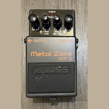 Černý kytarový efekt pedál značky BOSS, model Metal Zone MT-2. Horní část obsahuje čtyři ovládací knoflíky s popisky MIN MAX, -15 HIGH +15 LOW a 200…