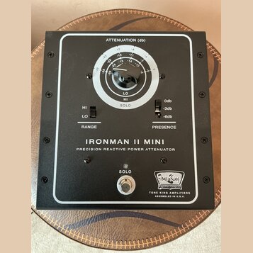 Černý přístroj s bílým rámečkem a nápisem IRONMAN II MINI PRECISION REACTIVE POWER ATTENUATOR. Obsahuje regulační knoflík s označením ATTENUATION (db…
