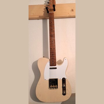 Elektrická kytara typu Telecaster s přírodním dřevěným povrchem těla a hmatníkem. Má bílý pickguard, jeden krkový snímač a jeden mostový snímač v kov…