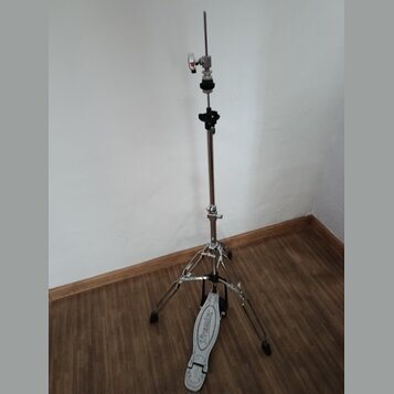 Stříbrný kovový stativ s černými plastovými prvky a tříramenou základnou. Na spodní části jedné z nožic je bílý plastový pedal s nápisem "Premier". P…