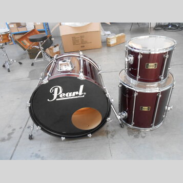 Sada bubnů v tmavě červené barvě. Na černém předním koži basového bubnu je bílý nápis Pearl®. Tom a floor tom mají na korpusu zlaté štítky s nápisem…