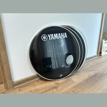 Tři černé kruhové kryty na basový buben s kovovým lemováním. Na předním krytu je bílý nápis YAMAHA a doprovodné logo značky. V dolní části předního k…