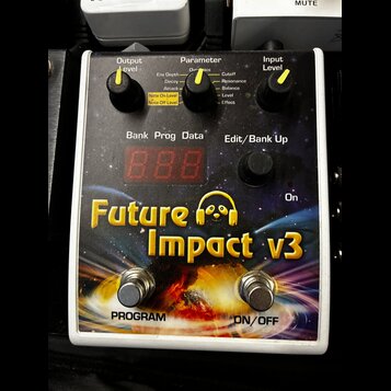 Bílý efekt pedál s barevným motivem vesmíru a nápisem Future Impact v3. Zařízení má tři otočné potenciometry s žlutými značkami označené jako Output…