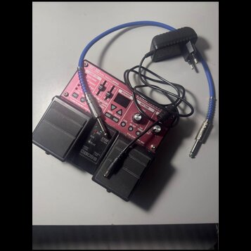 Červený pedál s nápisem RC-30 DUAL TRACK LOOPER a logem BOSS. Zařízení obsahuje řadu tlačítek, posuvníků a malý displej v horní části. K pedálu je př…
